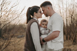 Familienshooting, Kind ist zwischen seinen Eltern wobei diese sich verliebt ansehen