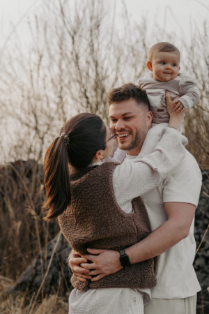 Familienshooting, Kind sitzt auf den Schultern seines Vaters und wird von der Mutter gehalten