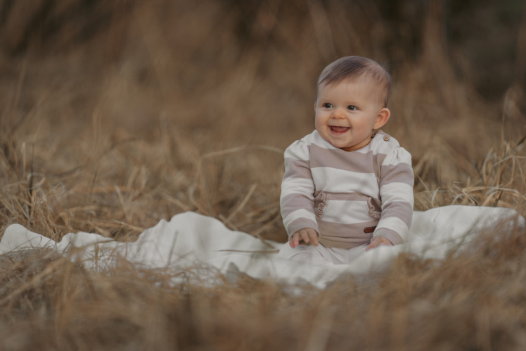 Familienshooting, Kind sitzt auf einer weißen Decke in einem Feld