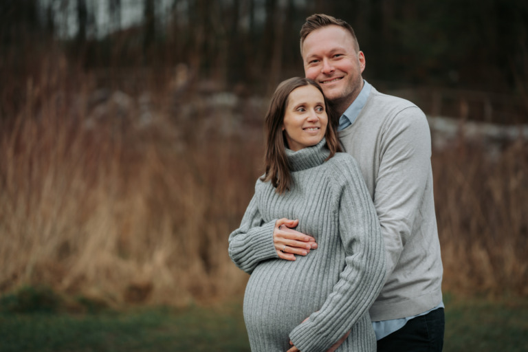 Babynewsfotoshooting, Mutter und Vater halten Babybauch